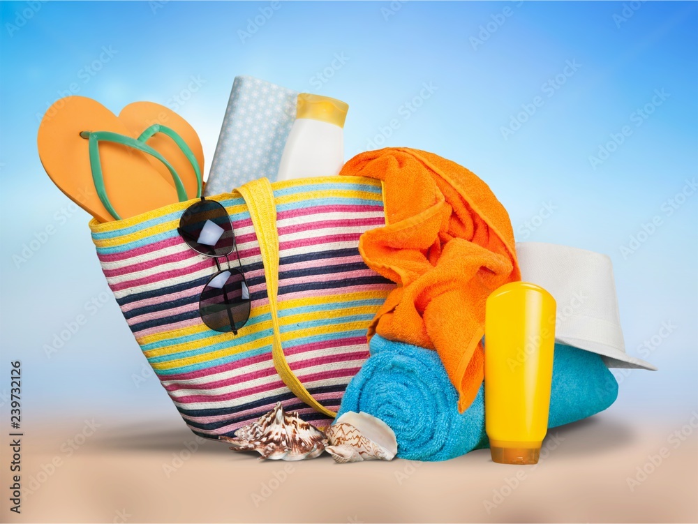 Colorful towels, cosmetics bottles and soap in basket, isolated