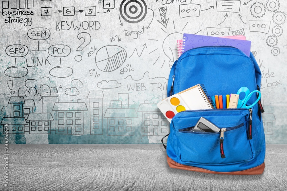 Open blue school backpack on wooden table in classroom