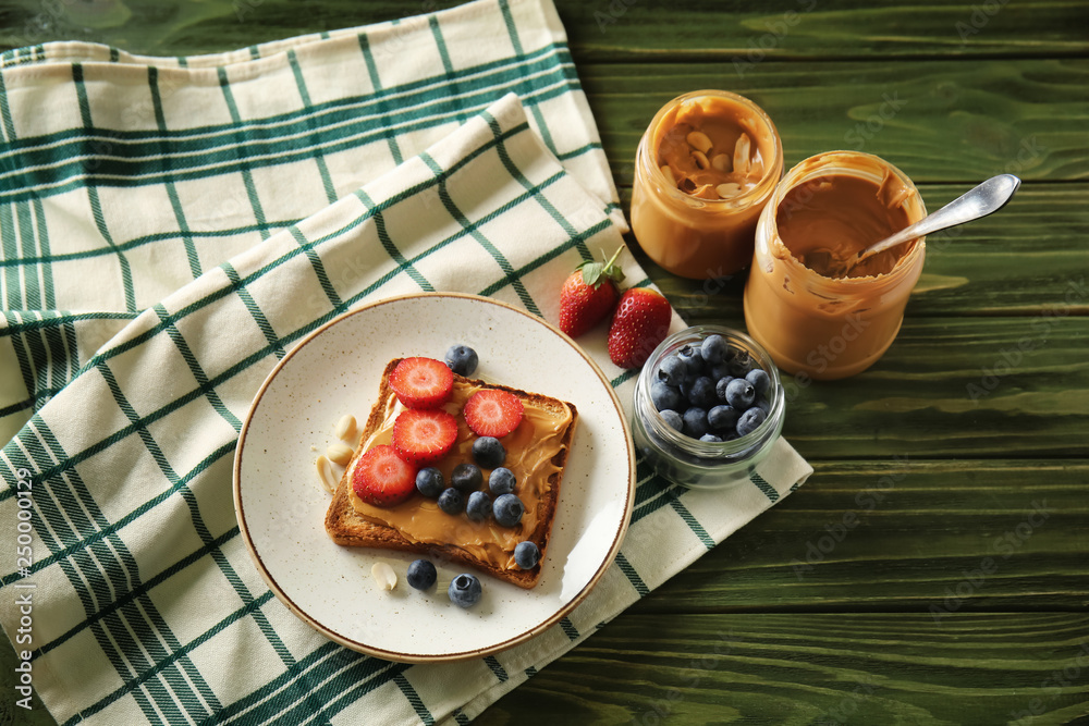 Toasted bread with tasty peanut butter and berries on wooden table