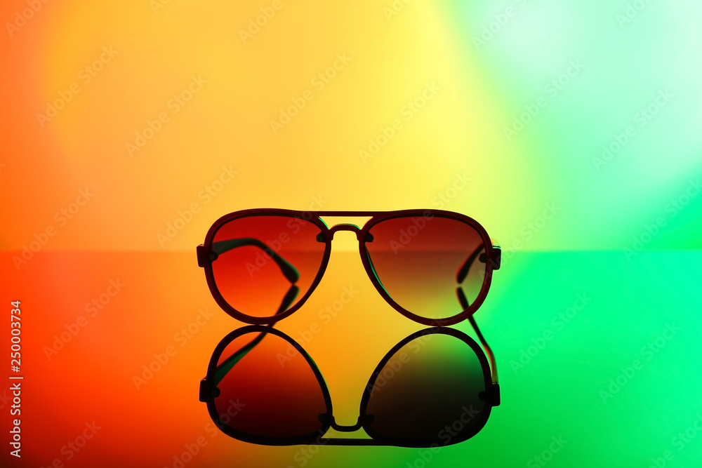 Modern sunglasses on color background