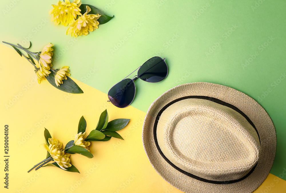 Hat, sunglasses and flowers on color background