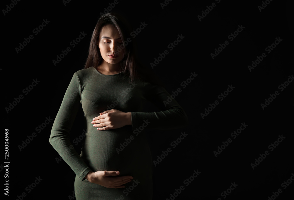 Portrait of beautiful pregnant woman on dark background