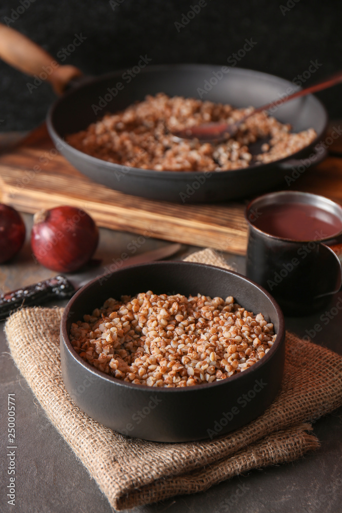 Bowl with tasty boiled buckwheat on grey table