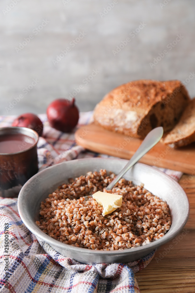 Bowl with tasty boiled buckwheat on wooden table