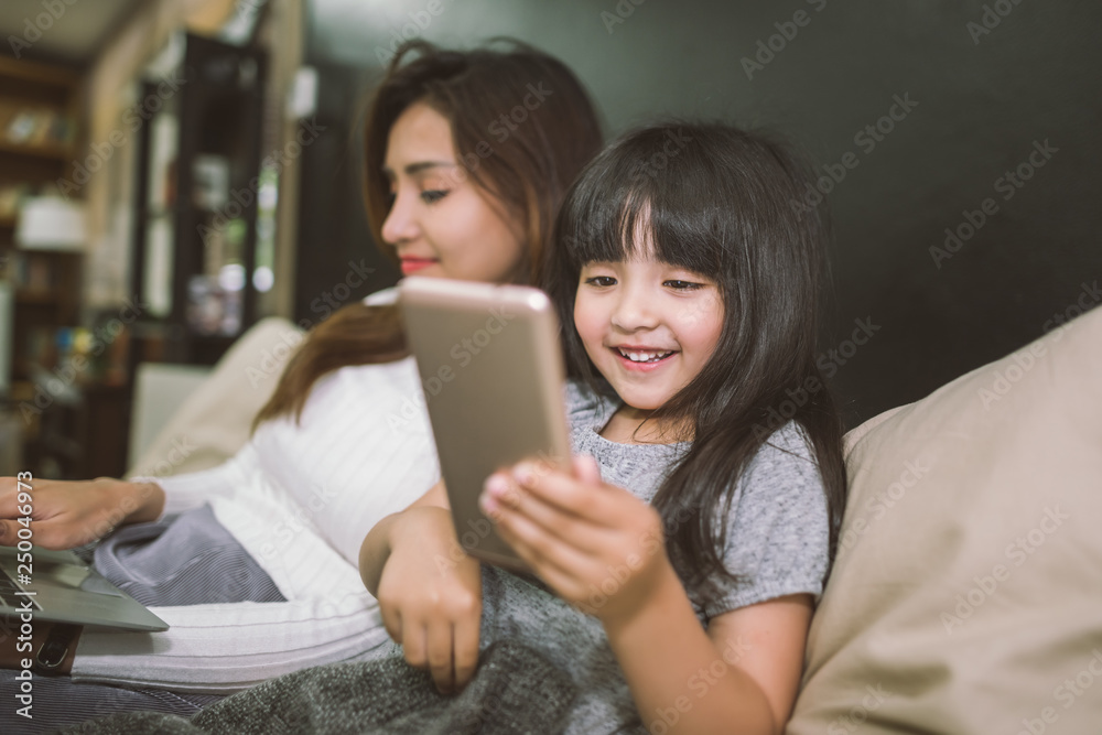 Mother and daughter using smartphone and laptop together in bedroom. technology concept