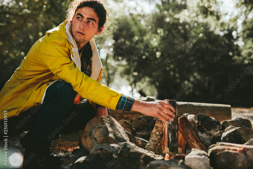 Man arranging fire wood for making a bonfire