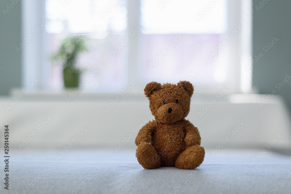 Plush teddy bear toy on white bed. Childhood concept