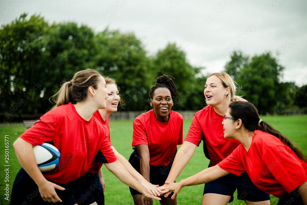 Female rugby players stacking their hands together