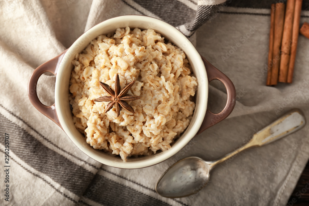 Pot with tasty oatmeal on table