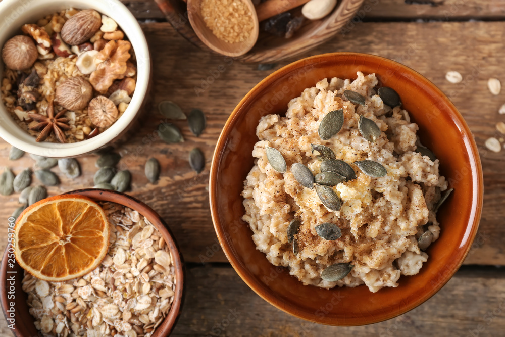 Bowls with tasty oatmeal and nuts on wooden table