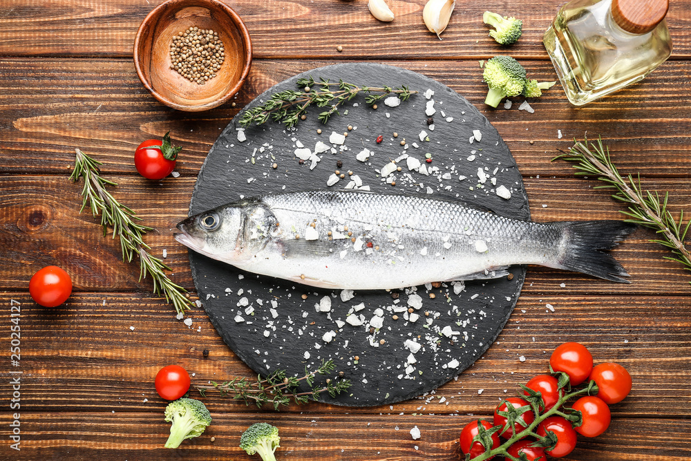 Slate plate with tasty seabass fish on wooden table