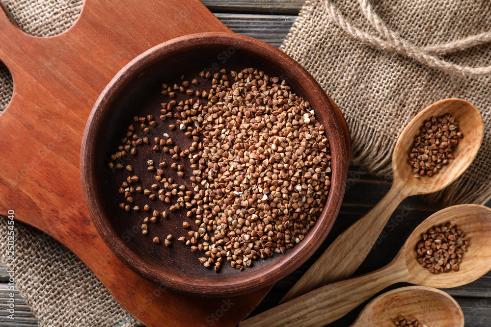 Bowl and spoons with raw buckwheat on table