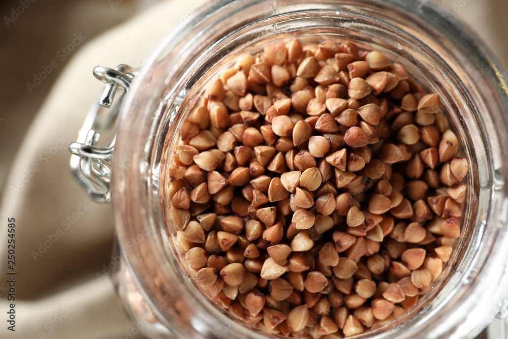 Glass jar with raw buckwheat, closeup