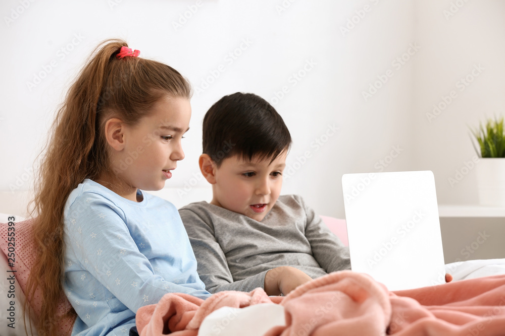 Cute little children with laptop watching cartoons at home