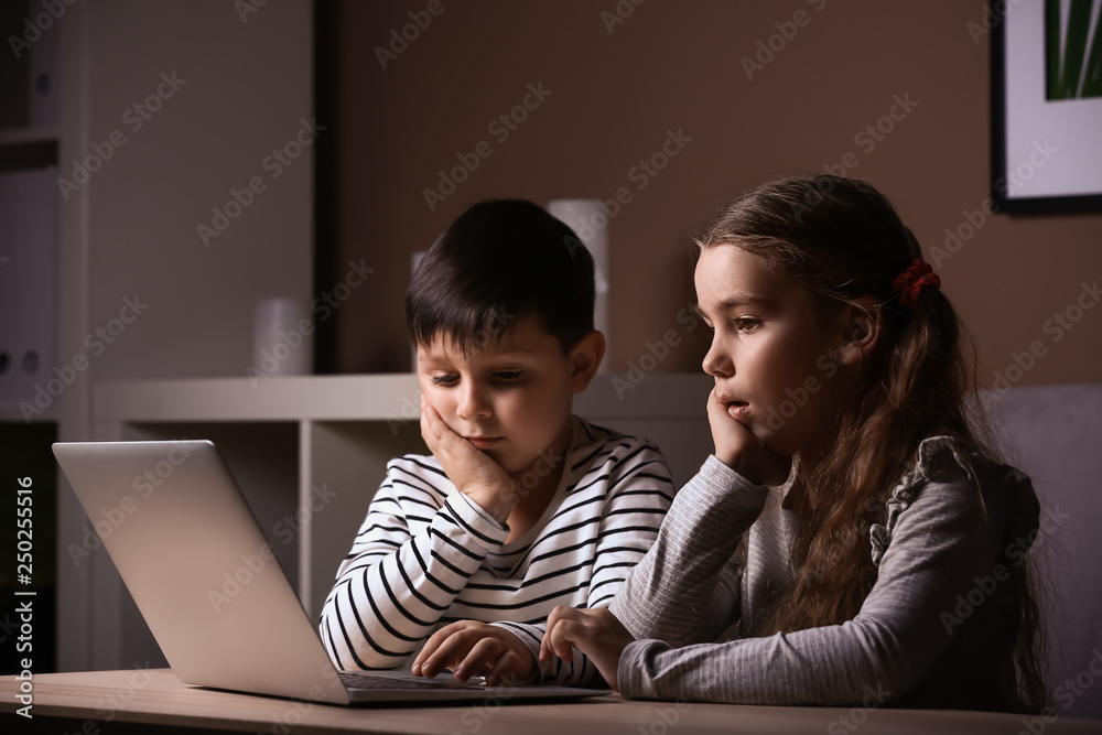 Cute little children with laptop watching cartoons late in evening