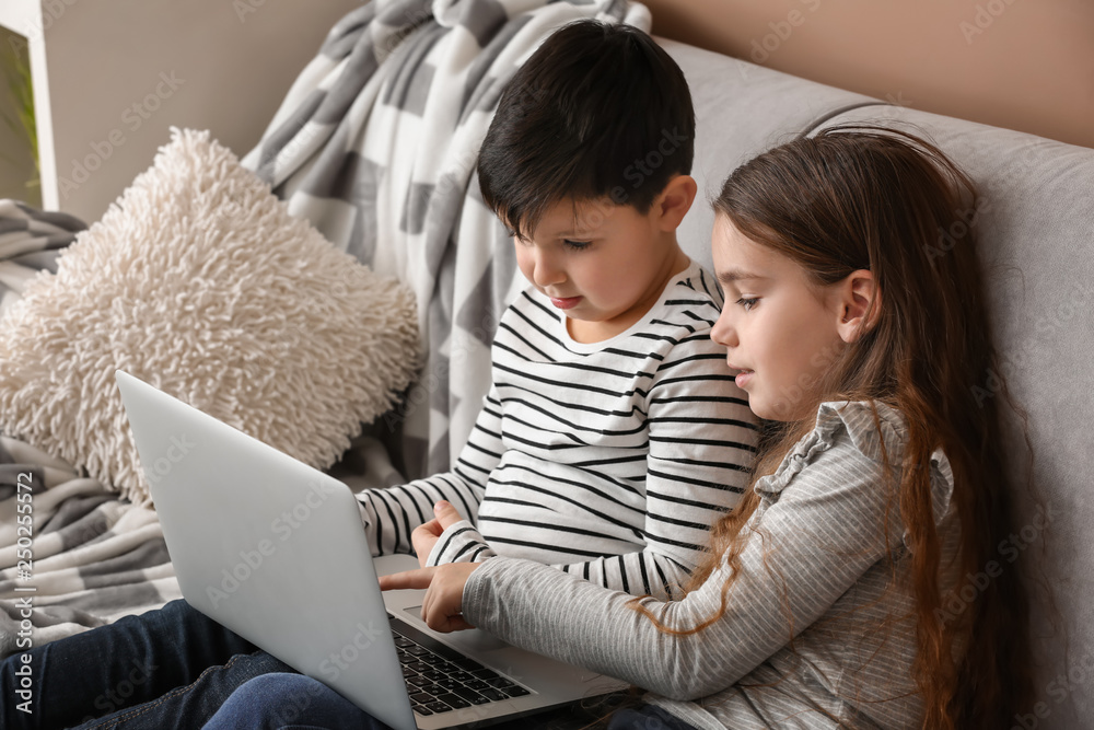 Cute little children with laptop watching cartoons at home