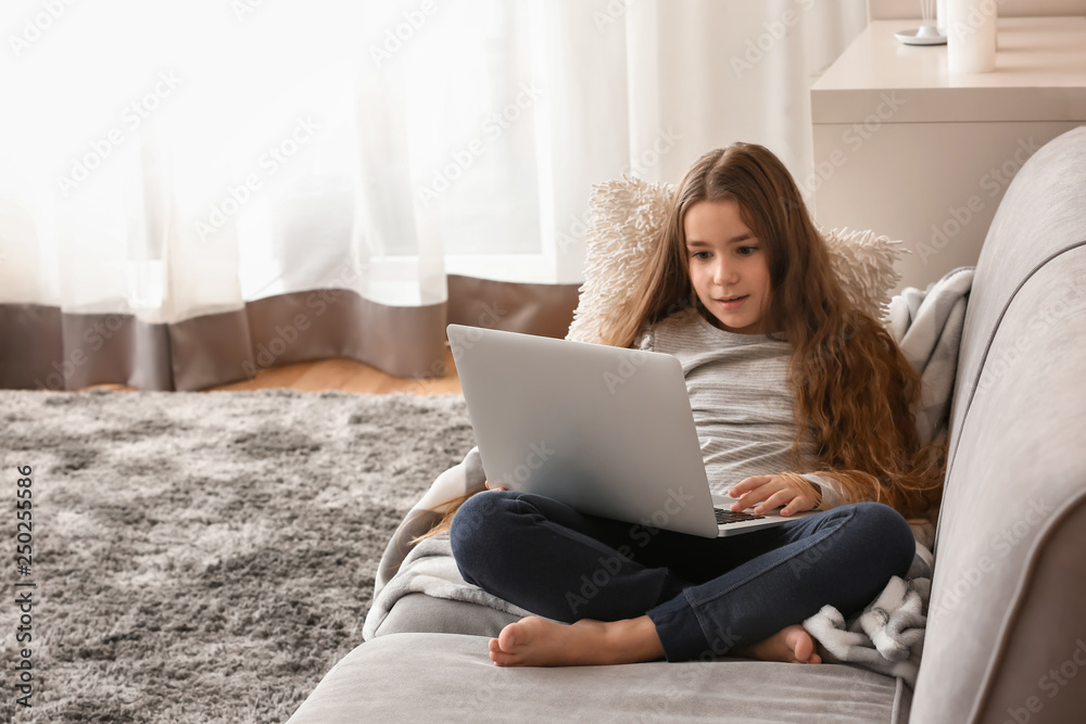 Cute little girl with laptop watching cartoons at home