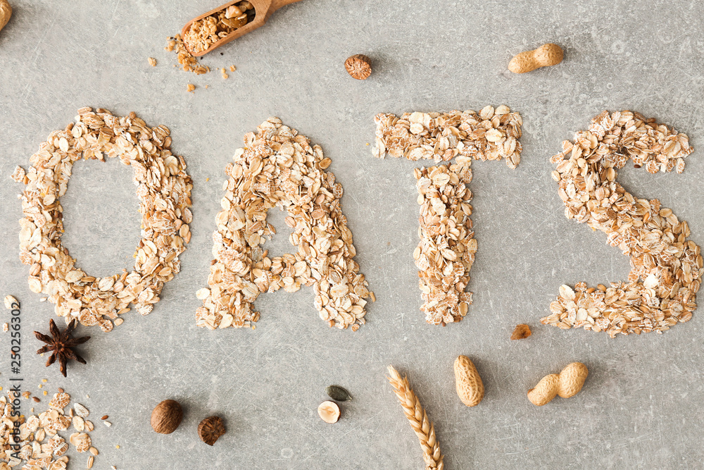 Word OATS made of flakes on grey table