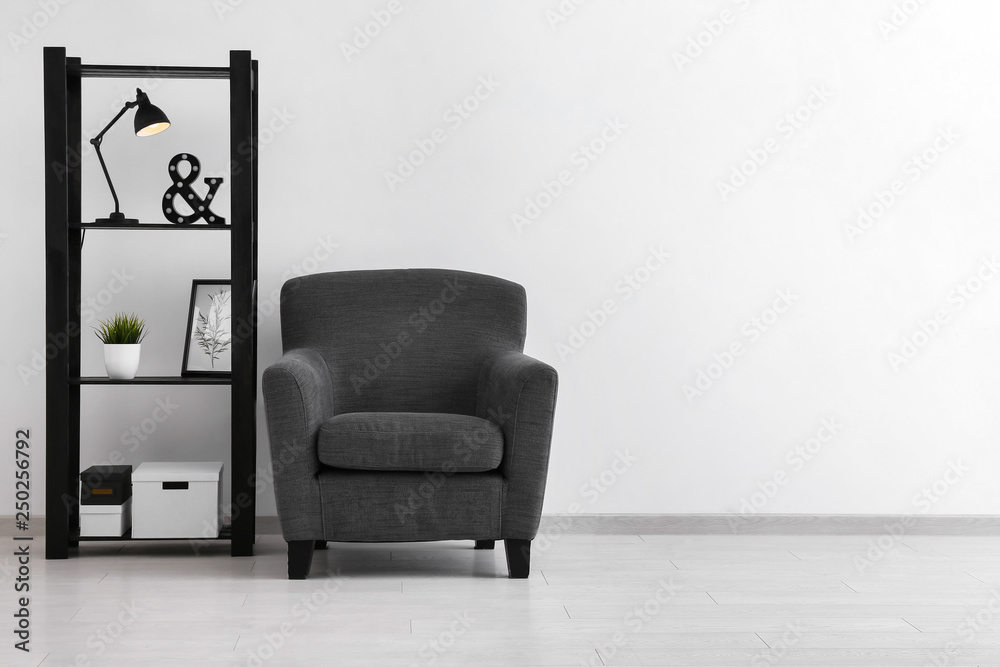 Comfortable armchair and shelf unit near white wall