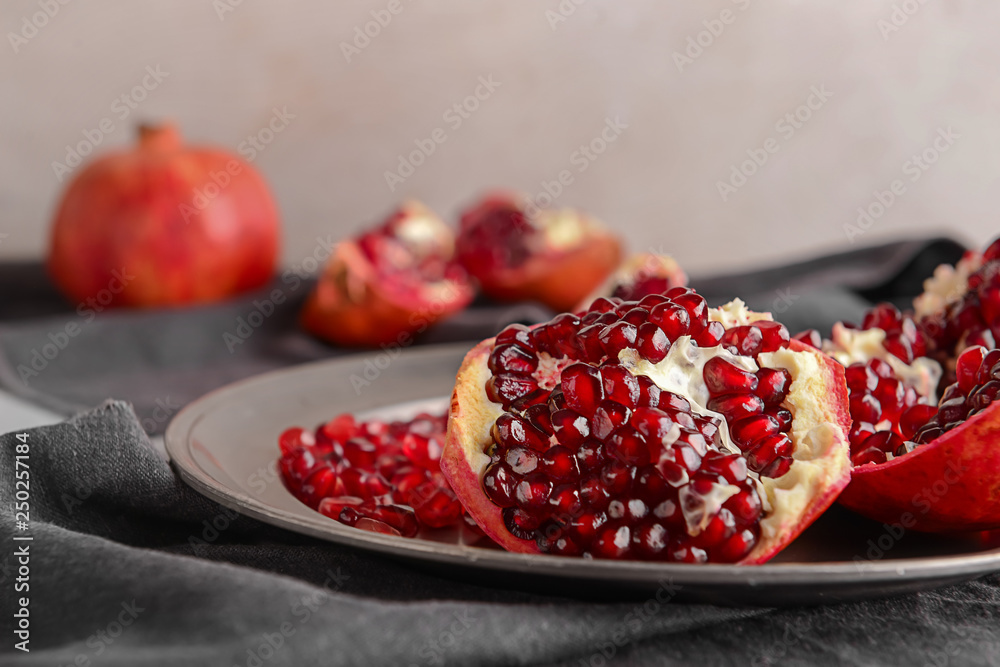 Plate with ripe pomegranate on table, closeup