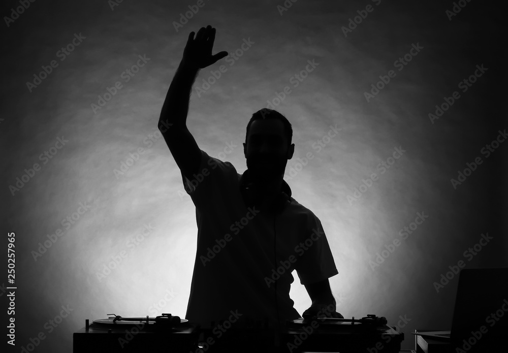 Silhouette of male DJ playing music on grey background