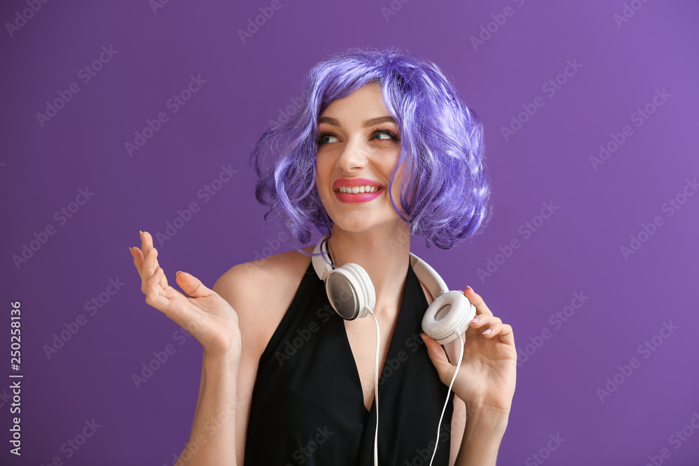 Beautiful young woman with headphones on color background