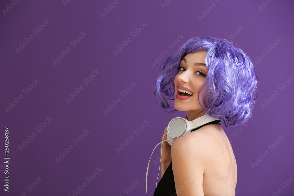 Beautiful young woman with headphones on color background