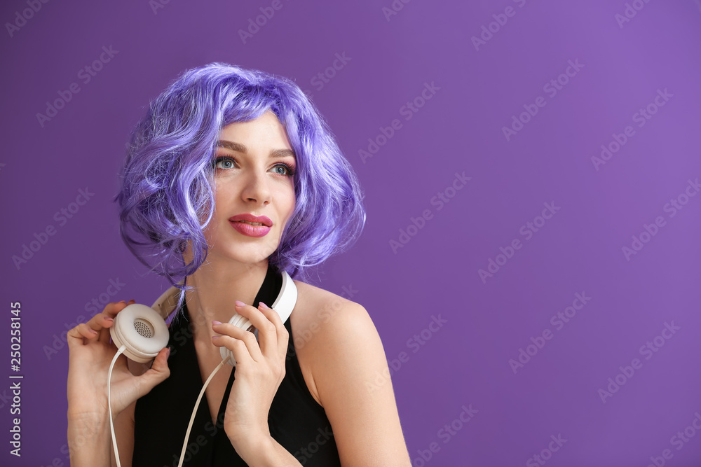 Beautiful young woman with headphones on color background