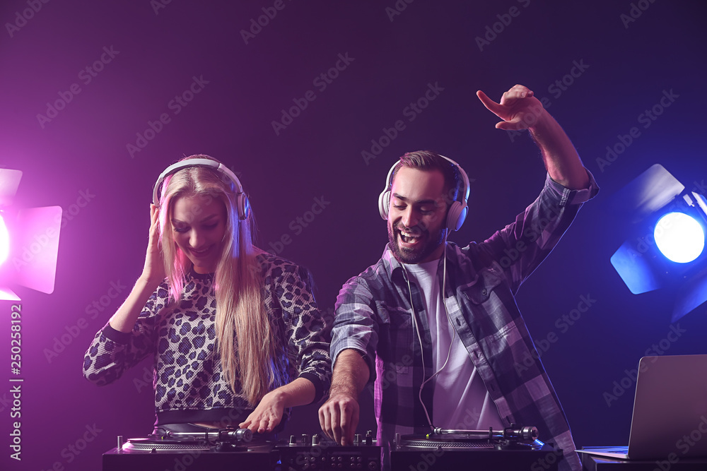 Male and female DJs playing music in club