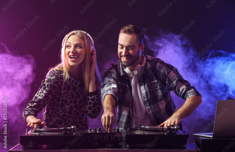 Male and female DJs playing music in club