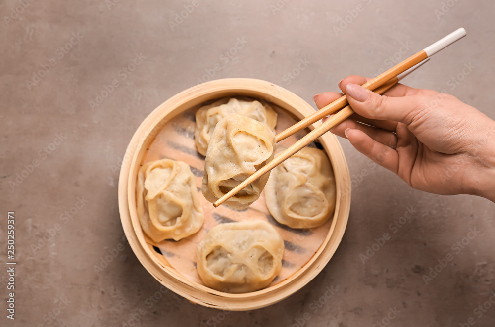 Woman eating tasty dumplings on grey background