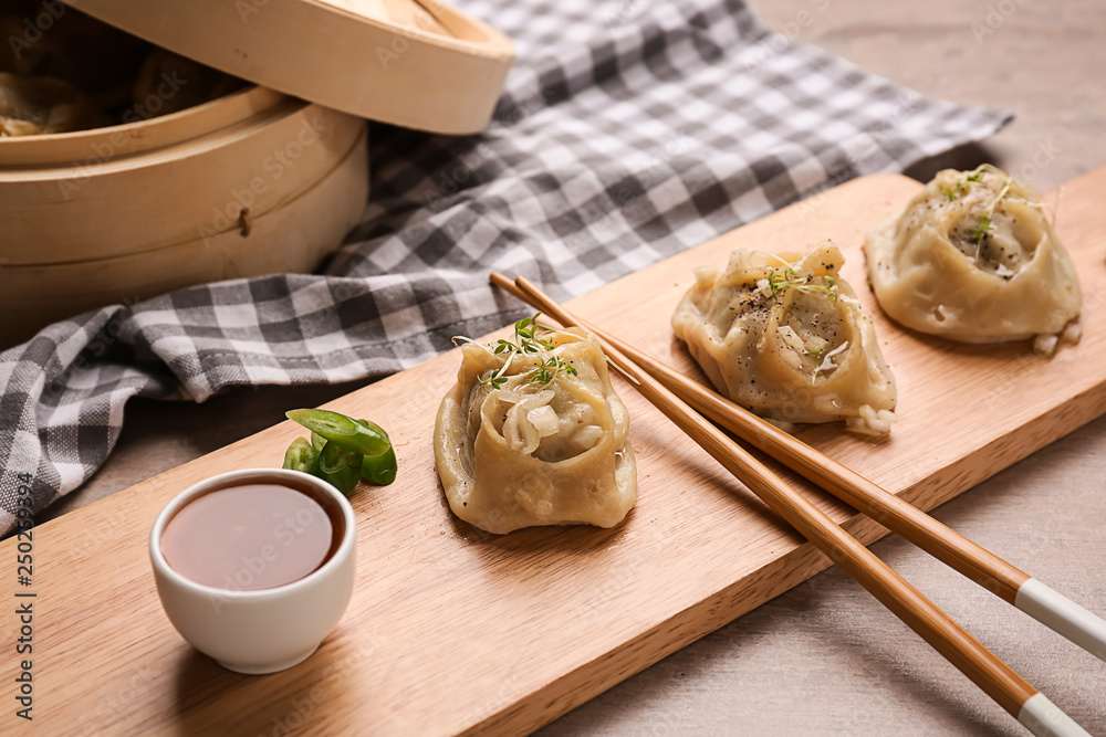 Wooden board with tasty dumplings on table