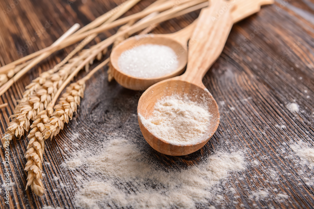 Spoons with flour on wooden table