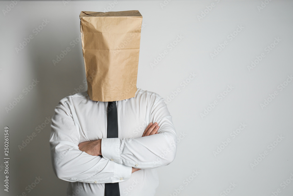 Businessman with paper bag on his head against light background