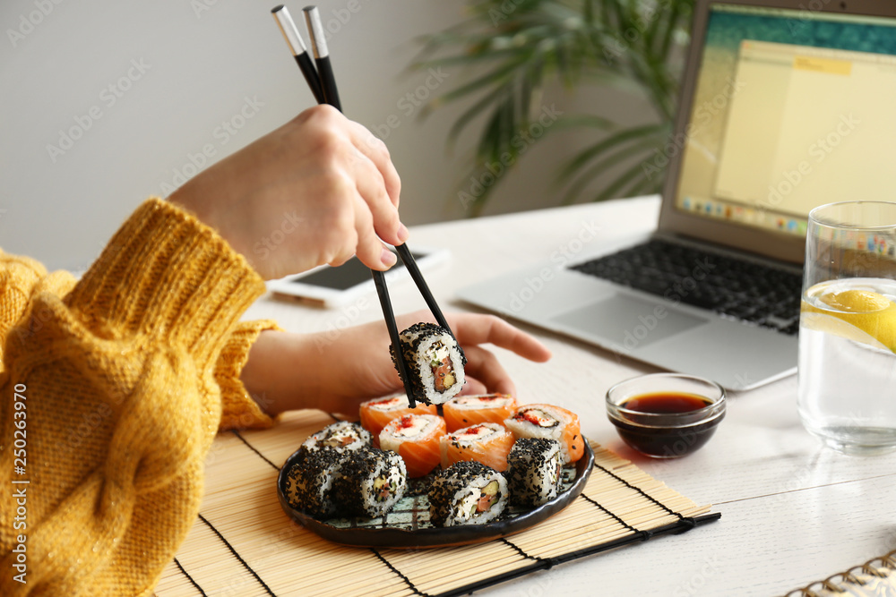 Woman eating tasty sushi rolls at home