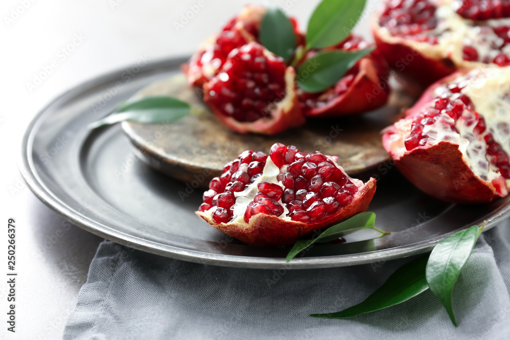 Plate with tasty pomegranates on table, closeup