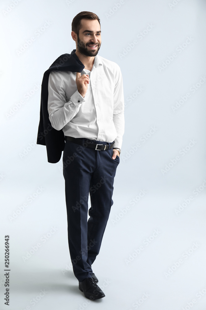 Handsome fashionable man in formal clothes against light background