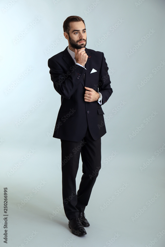 Handsome fashionable man in formal clothes against light background