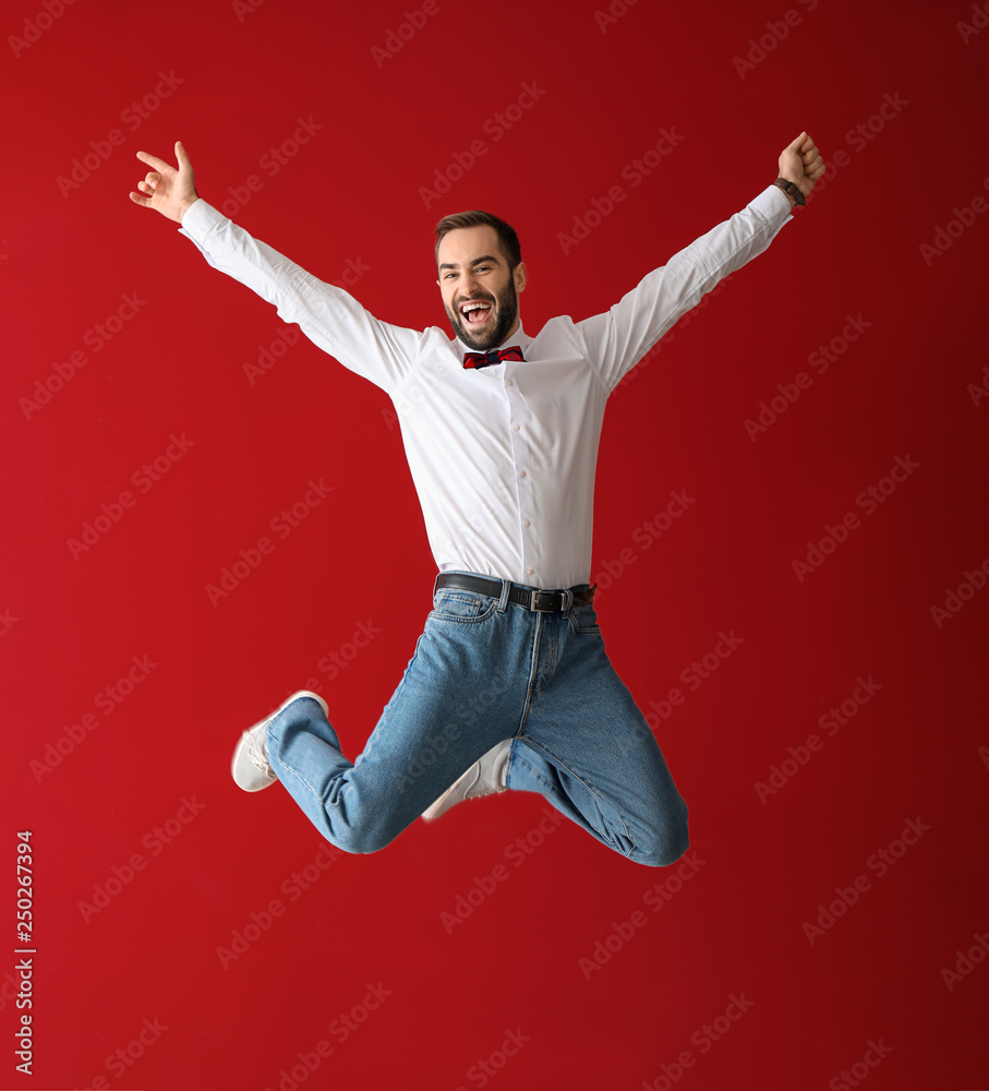 Handsome fashionable man jumping against color background