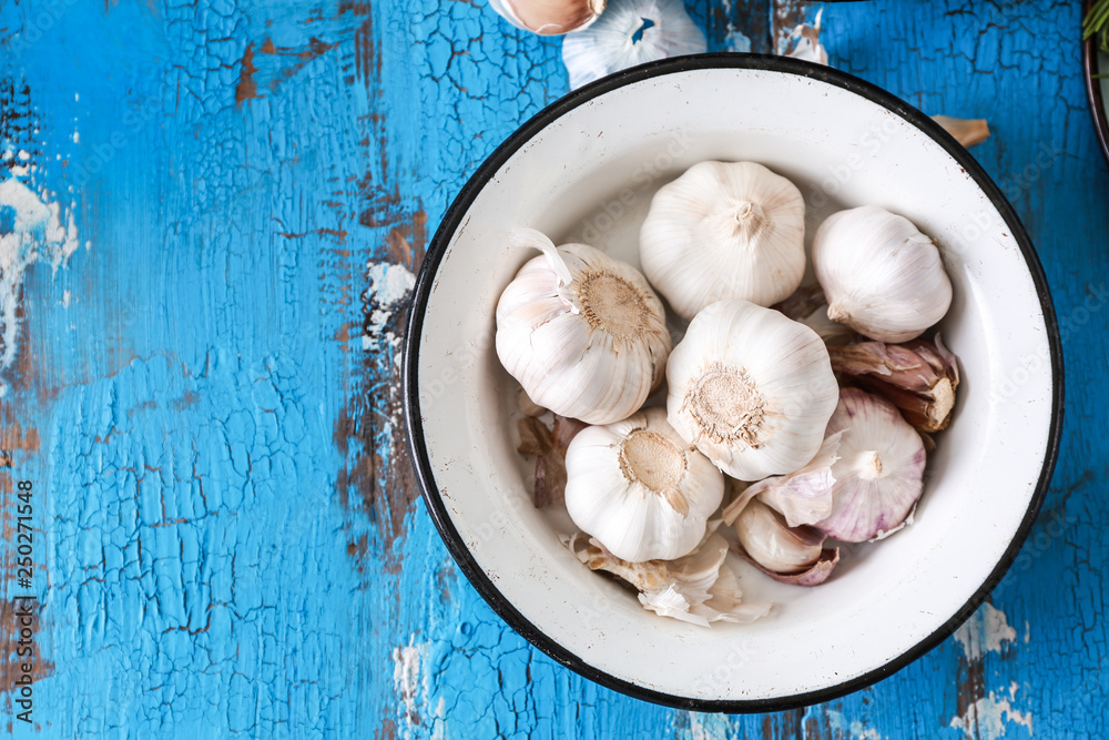 Bowl with fresh garlic on wooden background