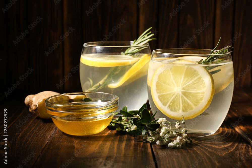 Glasses of fresh lemonade, honey and ginger on wooden table