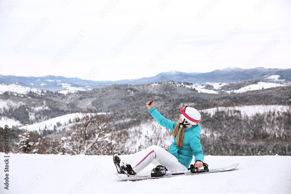 运动型女子在冬季度假胜地与滑雪板自拍