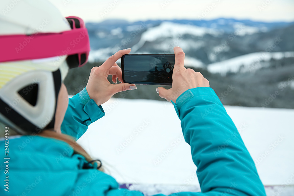 Sporty woman taking photo at winter resort