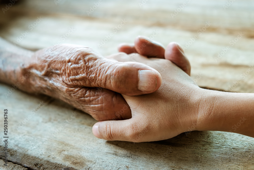 Hands of the old man and a childs hand on the wood table