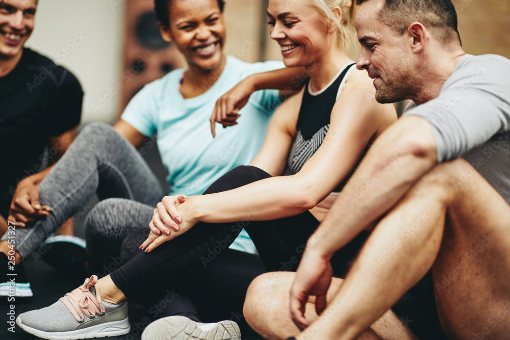 Diverse friends sitting in a gym laughing after working out