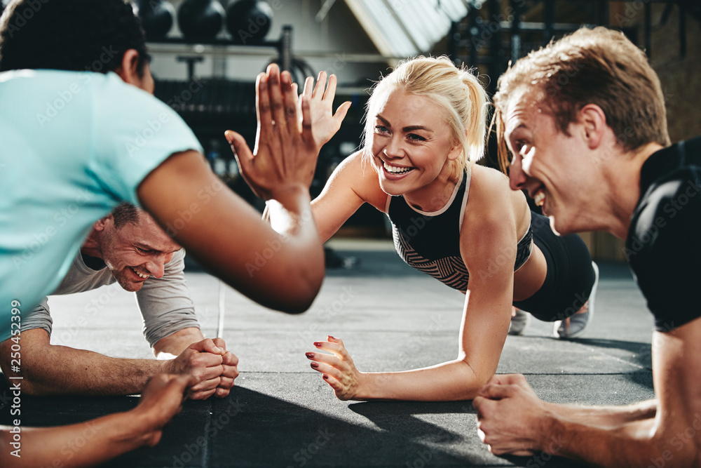 Two friends high fiving while planking on a gym floor