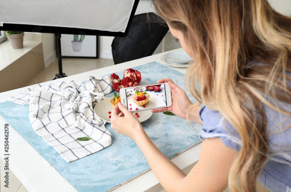 Female food photographer with mobile phone taking picture of tasty food