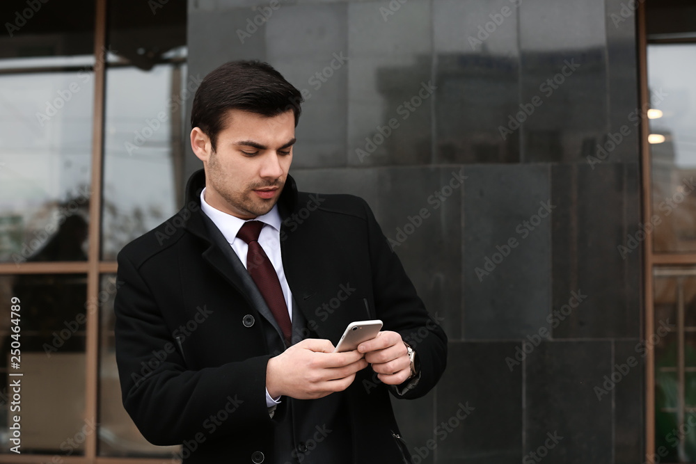 Portrait of handsome young businessman with mobile phone outdoors