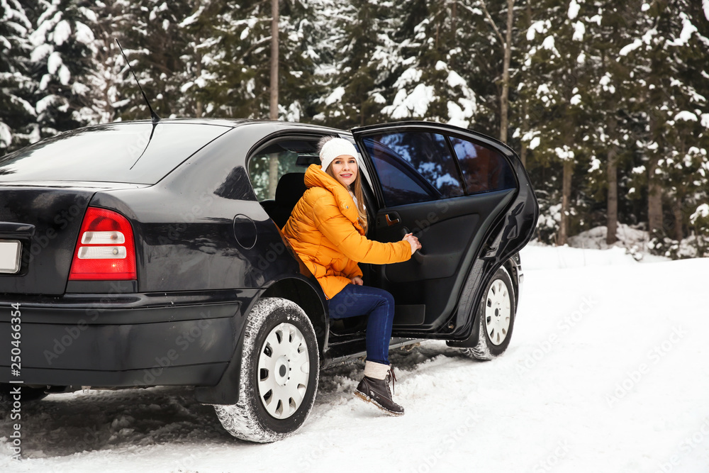 一名年轻女子在雪地冬季度假胜地下车