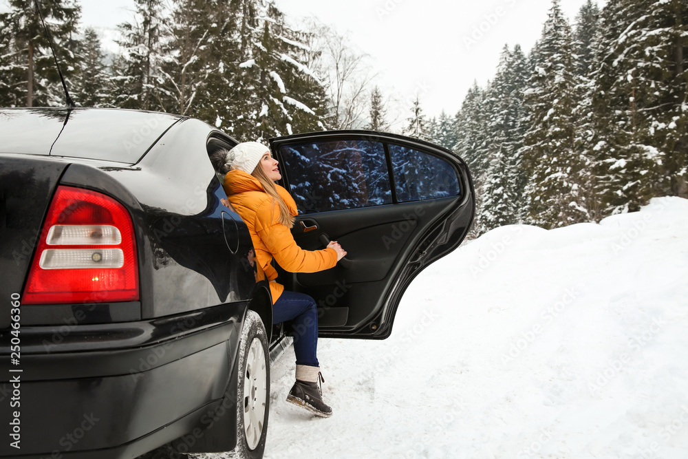 一名年轻女子在雪地冬季度假胜地下车